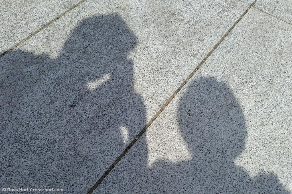 The shadows of two people on the concrete pavement
